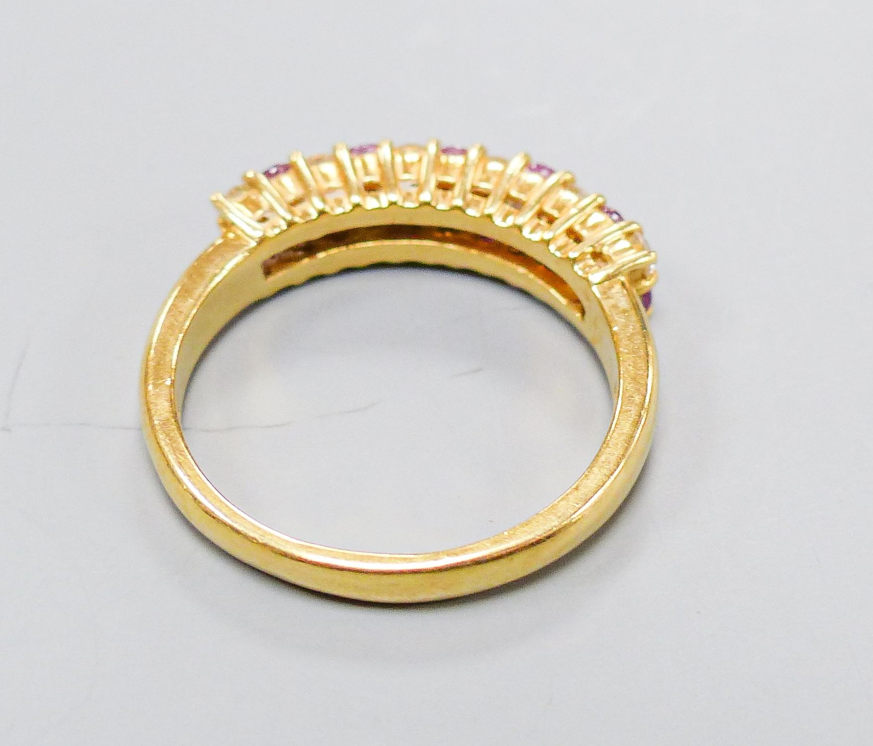 A modern 18ct gold, ruby and diamond set two row half hoop ring, size O, gross 5.3 grams.